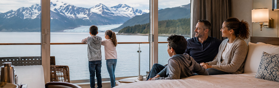 Mixed-race family enjoying Alaska scenery from a cruise ship balcony cabin
