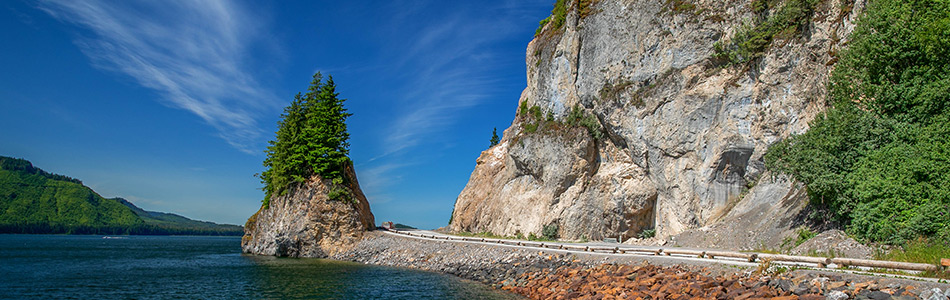 Scenic coastal road beside a rocky shoreline at Icy Strait Point, Alaska.