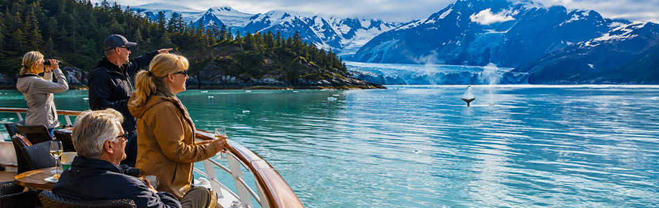 Luxury Alaska cruise guests enjoy glacier views and whale watching from an elegant ship deck.