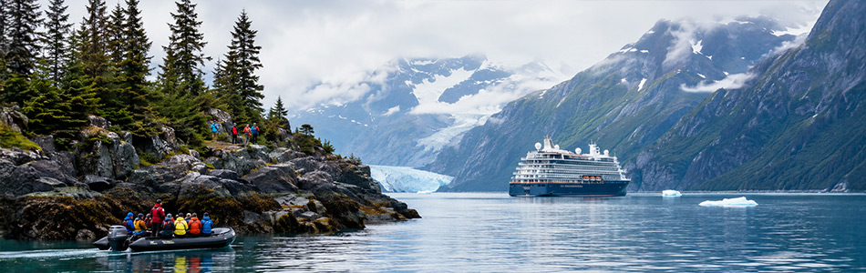 Small expedition boat and large cruise ship explore a glacier-lined Alaska waterway.