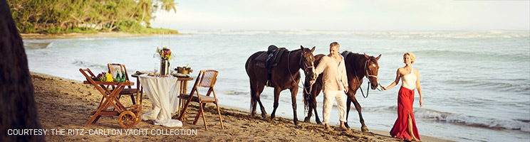Guests enjoying a luxury beach experience with horseback riding and private seaside dining during a Ritz-Carlton Yacht Collection voyage. Guests enjoying a luxury beach experience with horseback riding and private seaside dining during a Ritz-Carlton Yacht Collection voyage.