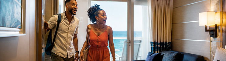 Couple arriving at their cruise ship balcony stateroom, excited to begin their vacation and enjoy ocean views from their private cabin. Couple arriving at their cruise ship balcony stateroom, excited to begin their vacation and enjoy ocean views from their private cabin.