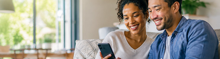 Couple using a smartphone to research travel options, plan a vacation, explore cruise deals, and book a cruise from the comfort of home. Couple using a smartphone to research travel options, plan a vacation, explore cruise deals, and book a cruise from the comfort of home.
